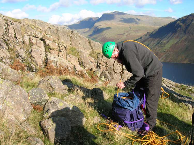 Tim packs a rope high on Long Crag, Middlefell, Wasdale. Scafell and Scafell Pike in distance